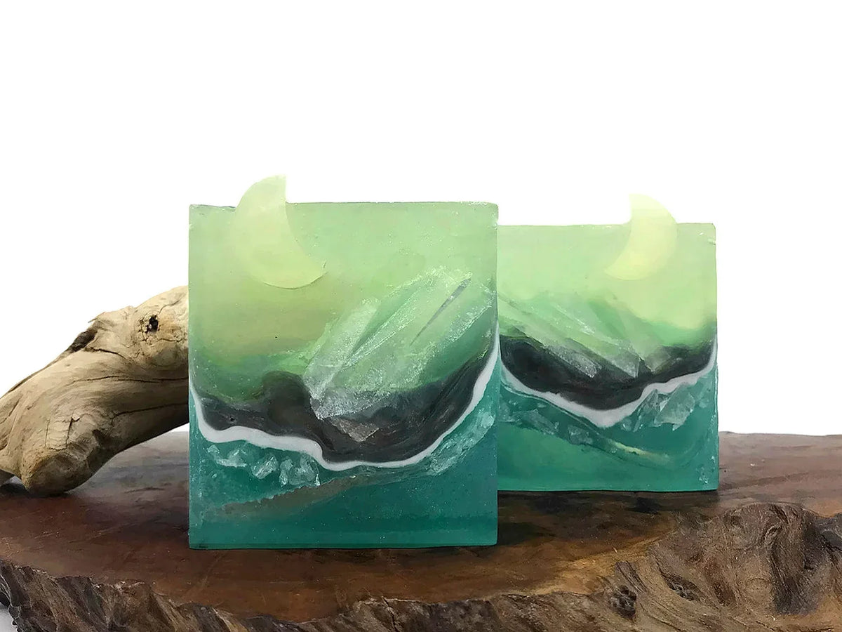 Handmade teal and green resin soap bars with crescent moon shapes and marbled waves.