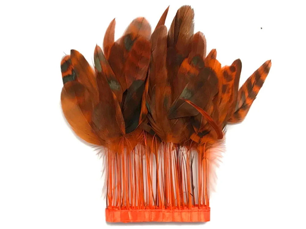 Vibrant orange and brown decorative feathers attached to an orange hair comb accessory.