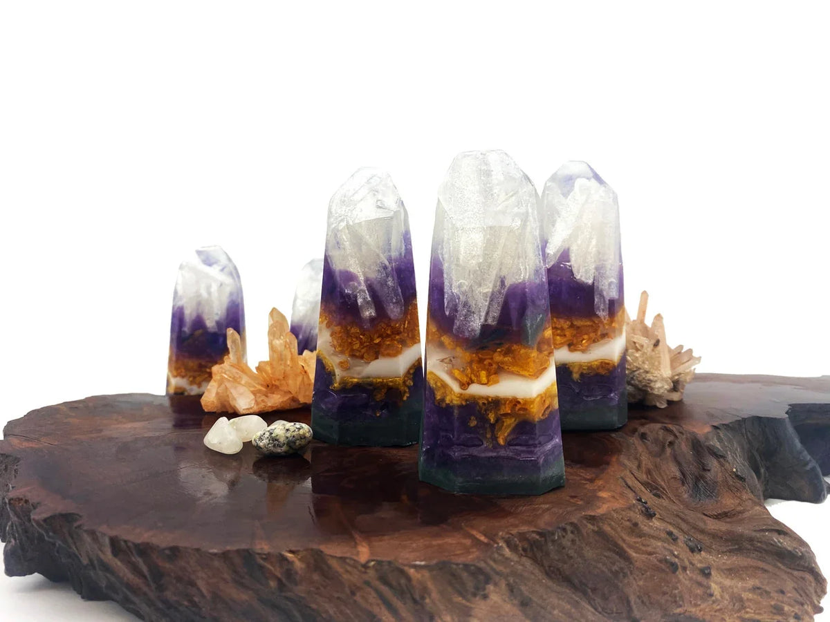 Purple amethyst and white quartz crystal towers on a rustic wooden base.