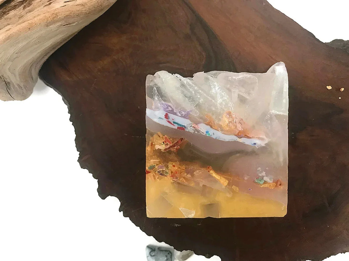 Artistic resin block with gold flakes and colorful embedded elements on wood.