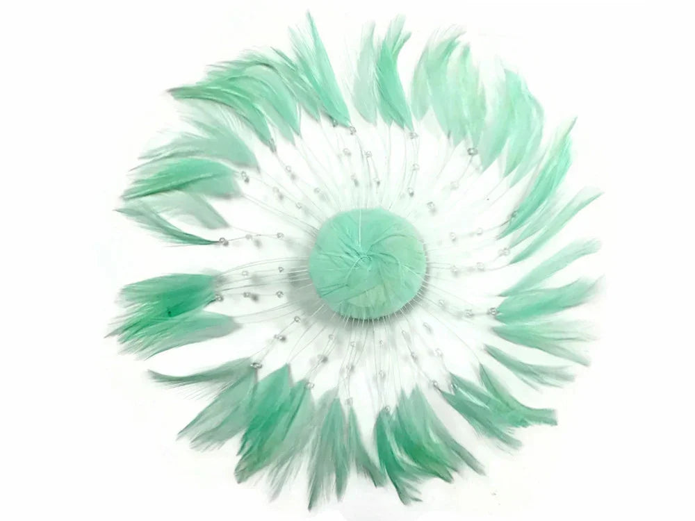Mint green feather hair accessory with delicate bead accents on a white background.