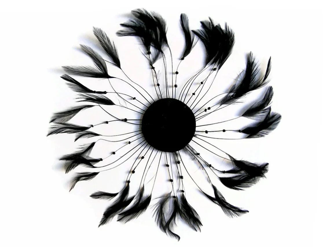Black feather wall decor in a circular floral arrangement on a white background.