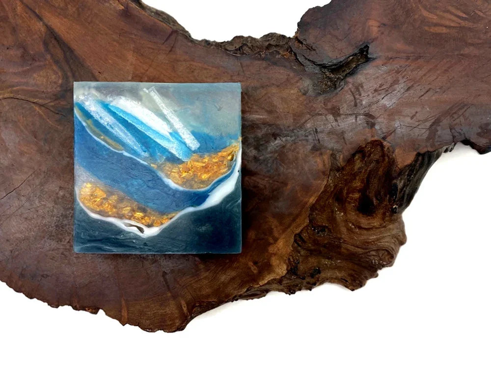 Blue and gold resin ocean art tile with gold leaf accents on a rustic wood base.