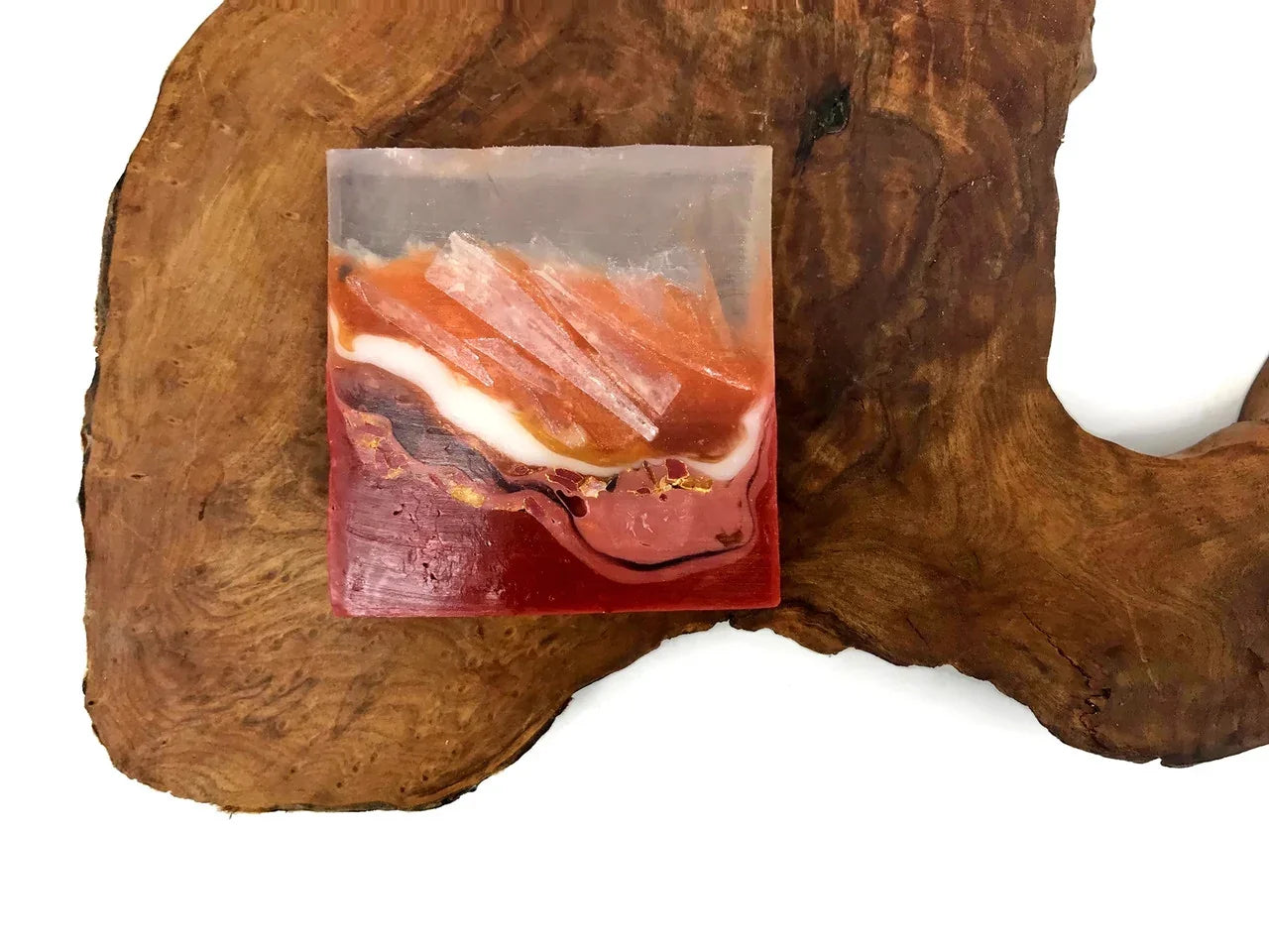 Square resin art piece with orange and red layers featuring embedded crystals on wood.
