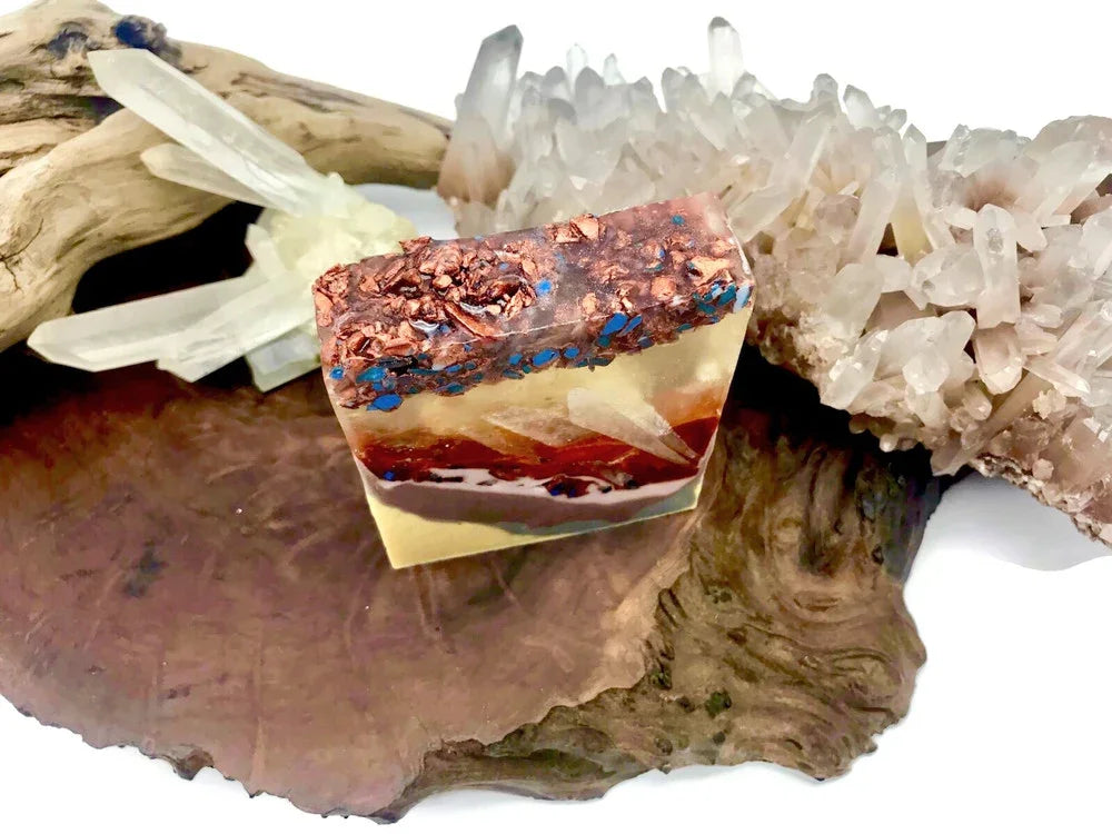 Artisan handmade soap bar with copper flakes and blue accents on a natural wood base.