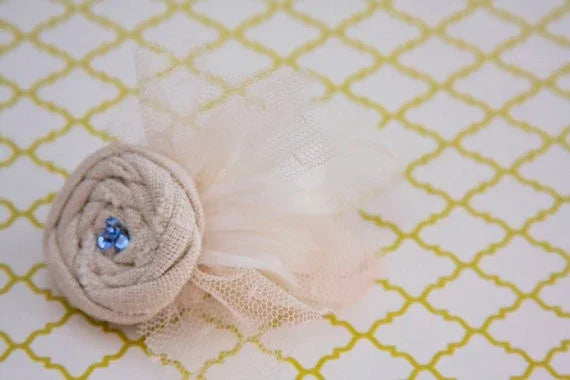 Cream fabric rose hair accessory with blue rhinestones and delicate tulle feathers.