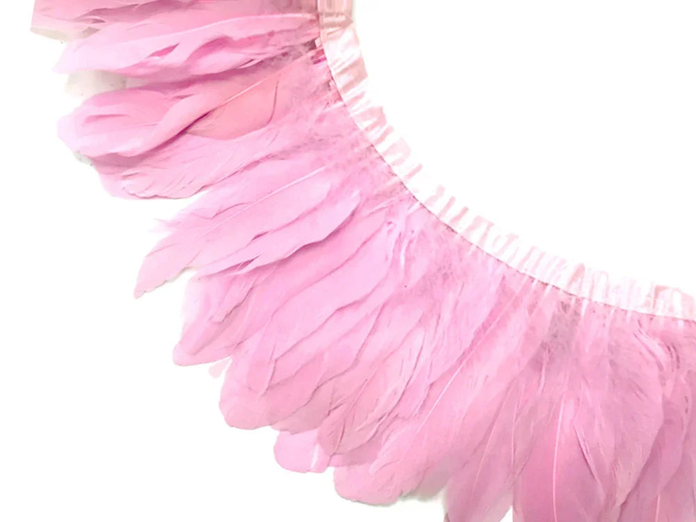Soft pink craft feathers attached to a decorative trim for DIY fashion and decor.