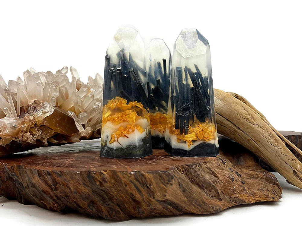 Handcrafted resin crystal towers with black tourmaline and gold leaf accents on wood.