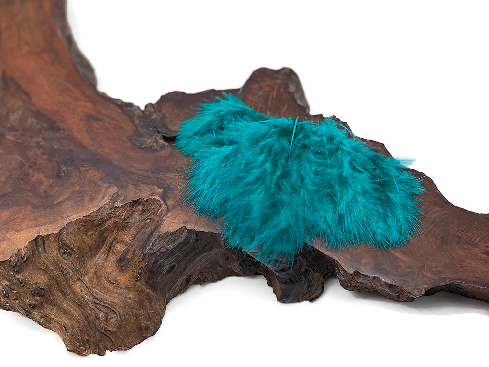 Peacock green turkey marabou feathers displayed on a rustic wooden slab.