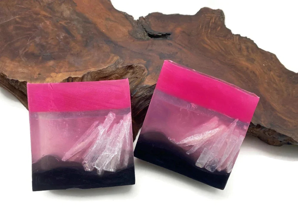 Pink and purple resin coasters with white crystal inclusions on a wooden base.