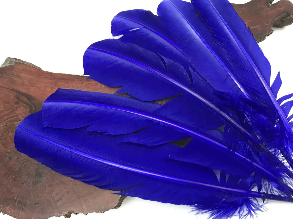 Vibrant cobalt blue feathers for DIY crafts and fashion decor on a wooden base.