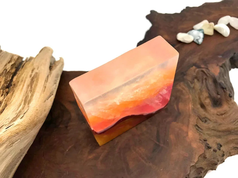Rectangular peach and orange translucent resin decor piece on a dark wood slice.