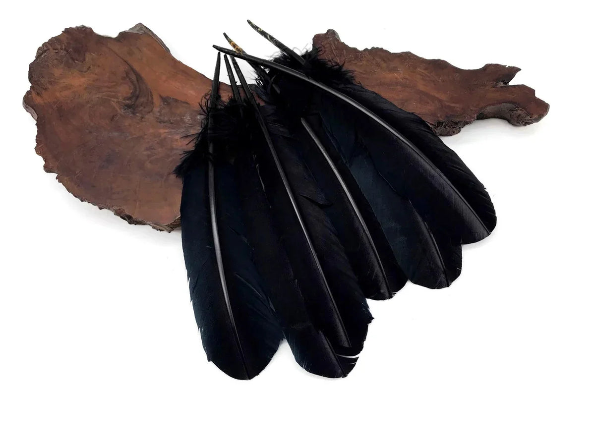 Elegant black feathers for DIY crafts and fashion decor on a rustic wood slice.