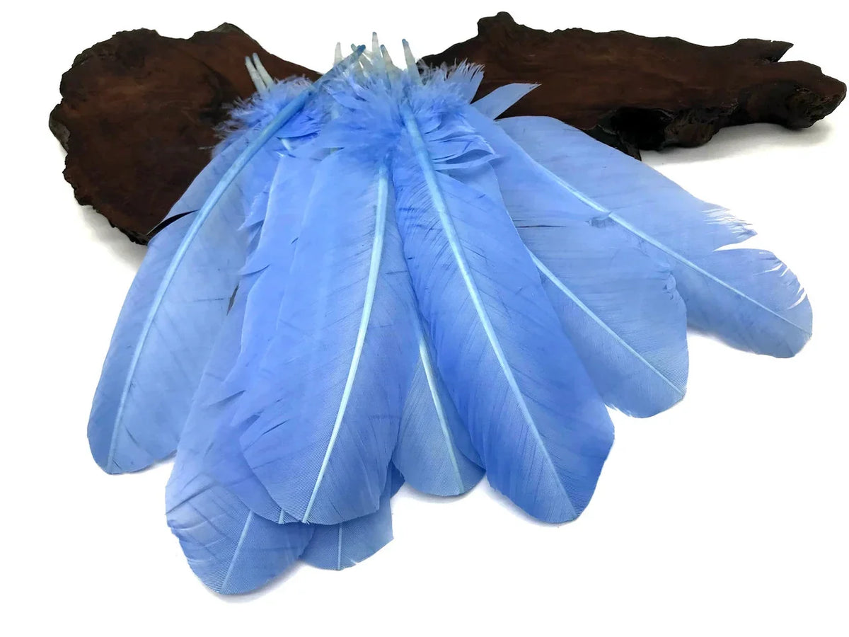 Vibrant light blue craft feathers arranged on a dark wood base for DIY fashion and decor.