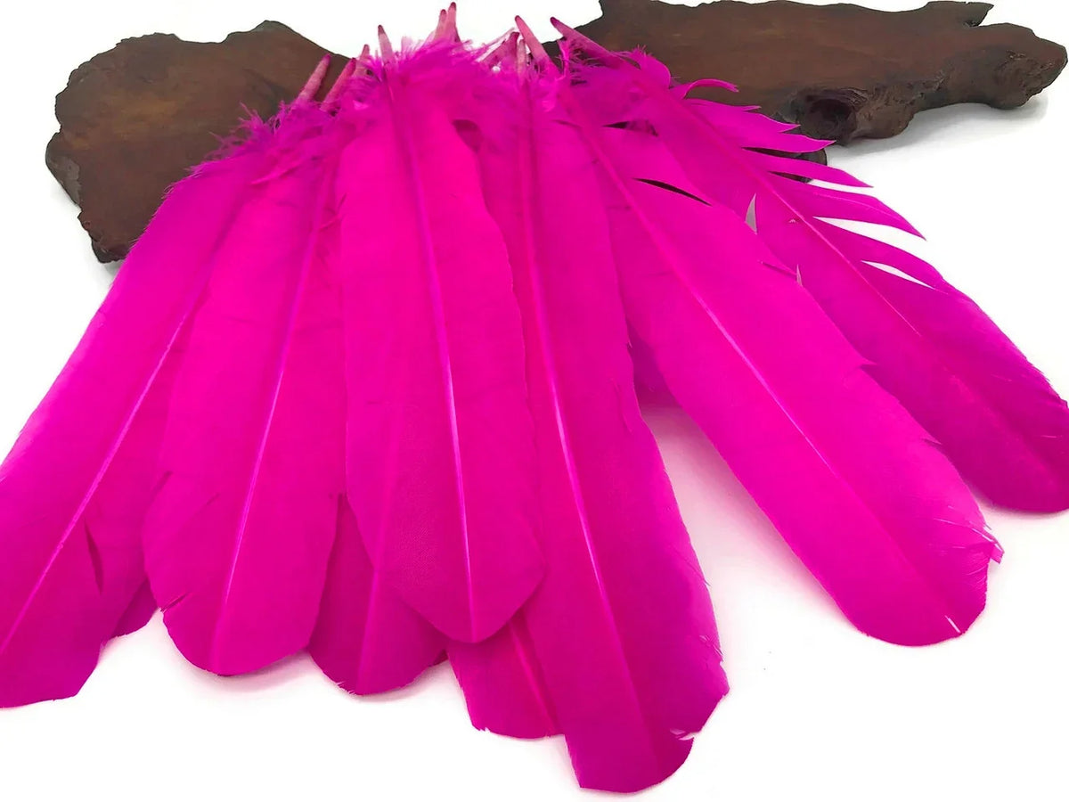 Vibrant hot pink craft feathers arranged on a dark wooden base for DIY decor.