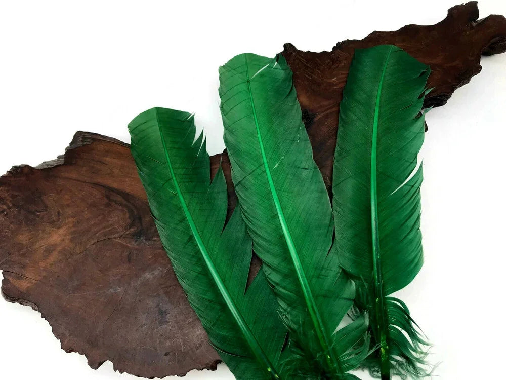 Three vibrant green craft feathers displayed on a natural dark wood slice.