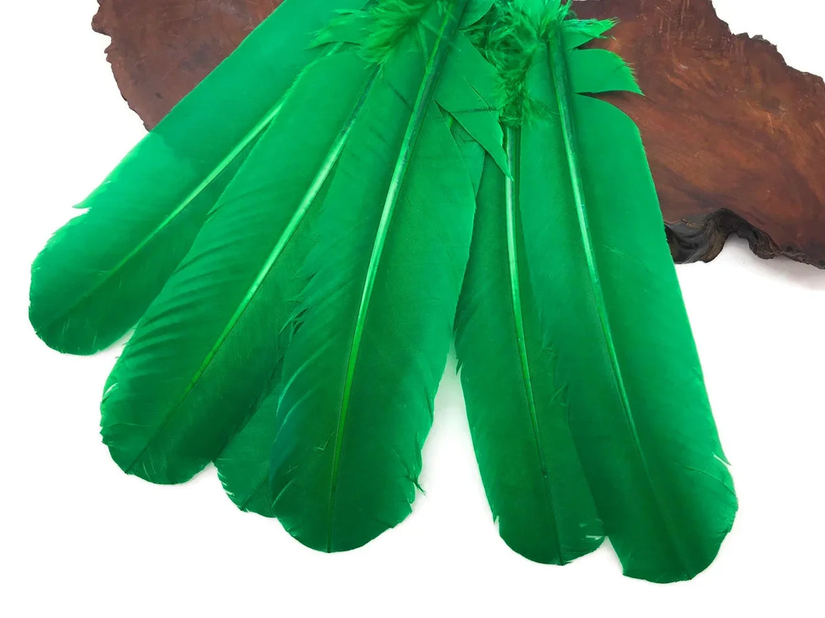 Vibrant green dyed craft feathers displayed on a natural wood slice.