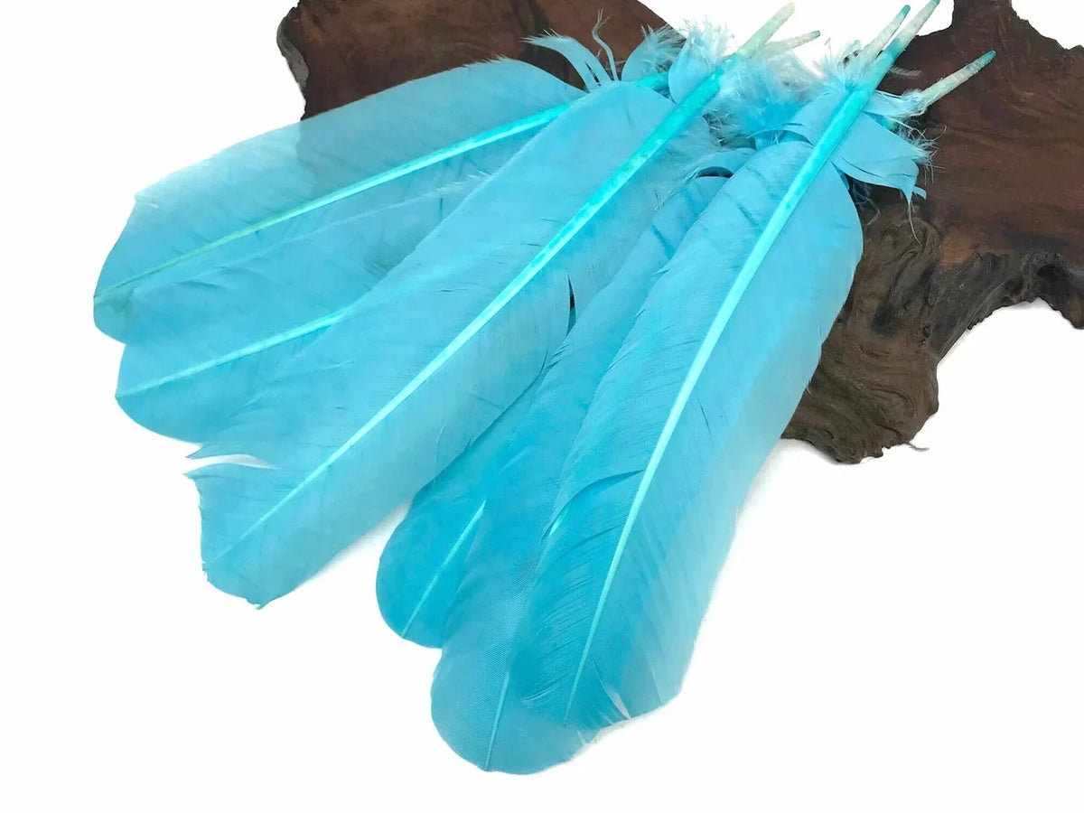 Vibrant turquoise blue feathers for DIY crafts and fashion decor on a wooden base.
