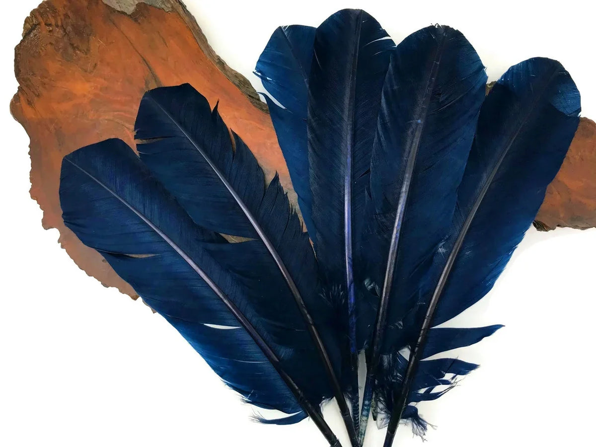 Deep navy blue craft feathers displayed on a natural wood slice background.