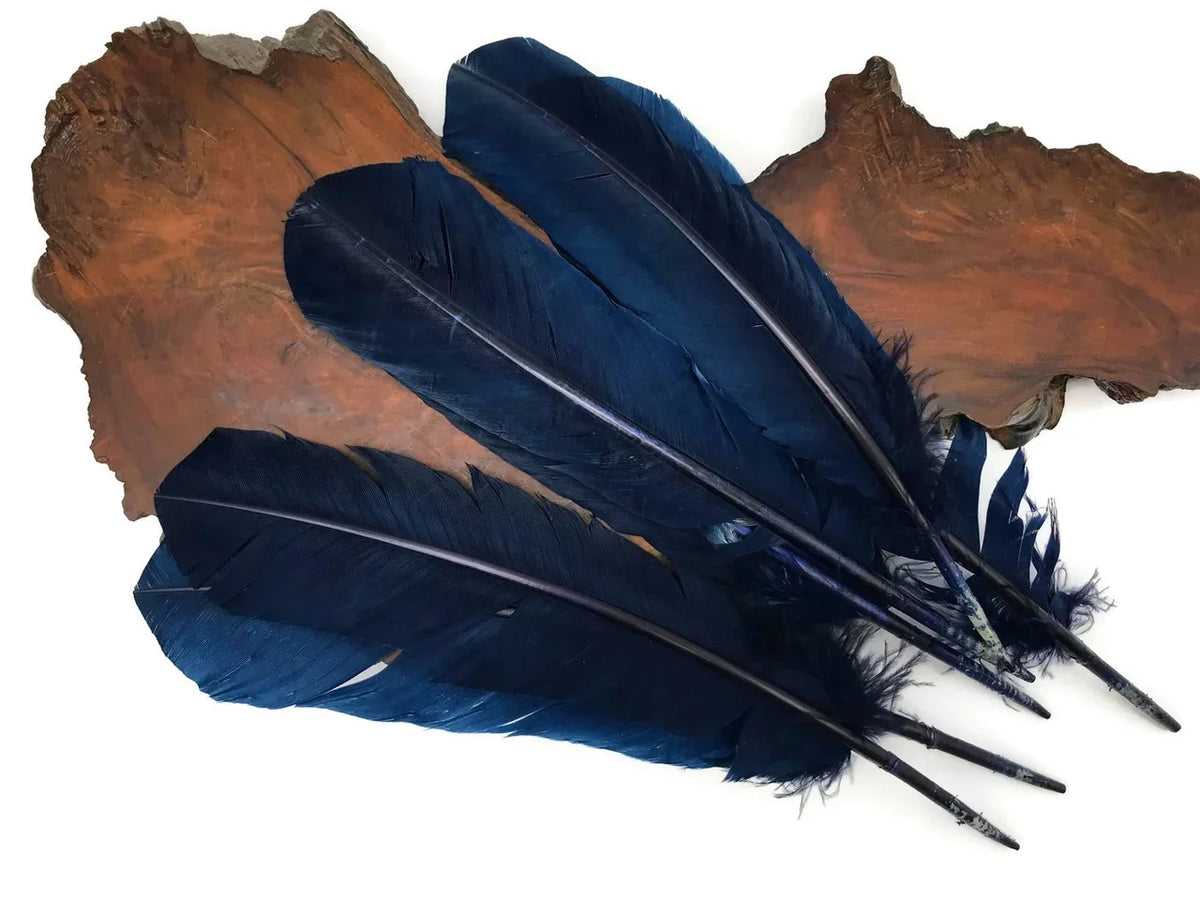 Deep blue decorative feathers laid on a natural wood slice background for crafts.