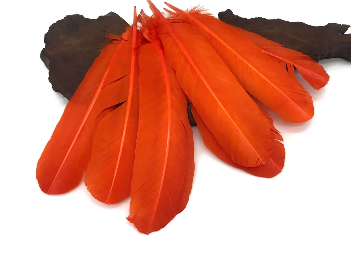 Vibrant orange dyed feathers for DIY crafts and fashion decor on a dark textured base.