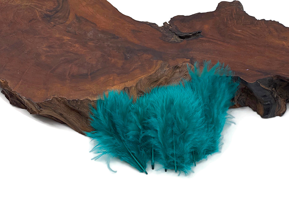 Peacock green turkey marabou feathers displayed on a rustic wooden slab.