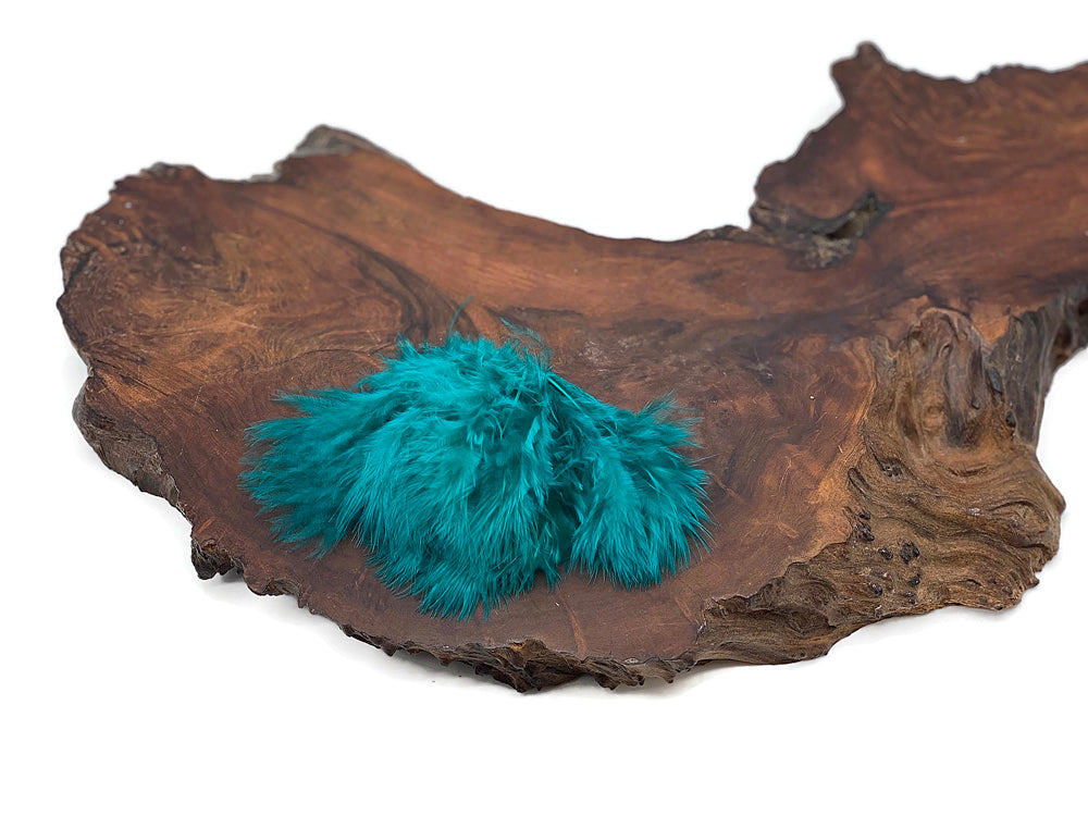 Peacock green turkey marabou feathers displayed on a rustic wooden slab.