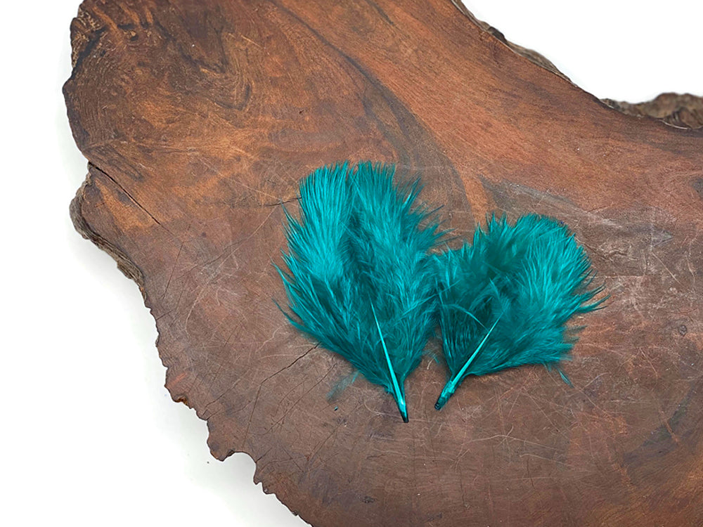 Peacock green turkey marabou feathers displayed on a rustic wooden slab.