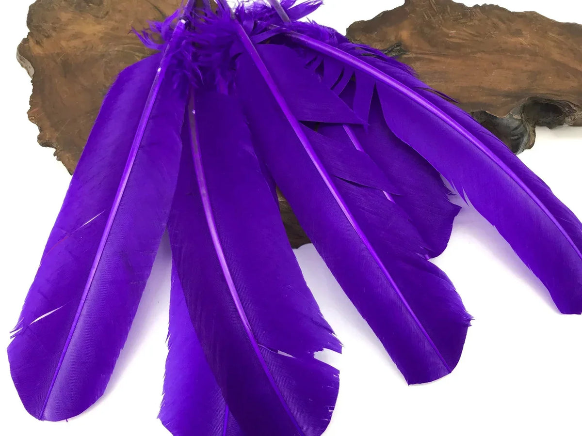 Vibrant purple craft feathers displayed on a natural wood slice background.