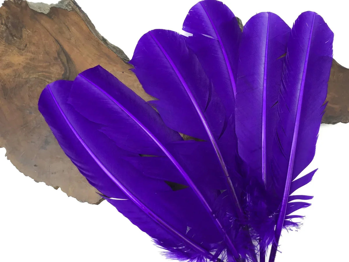 Vibrant purple craft feathers arranged on a natural wood slice background.