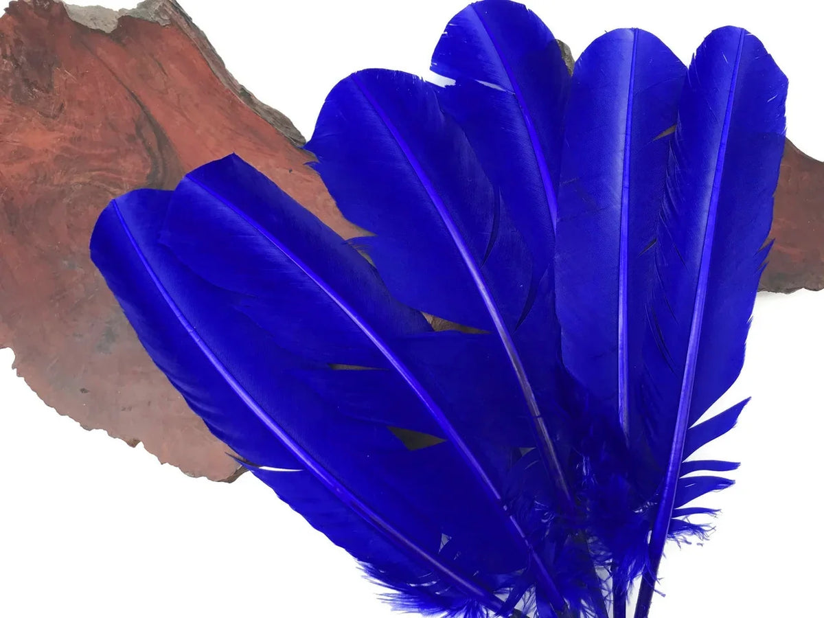Vibrant cobalt blue craft feathers arranged on a natural wood slice background.