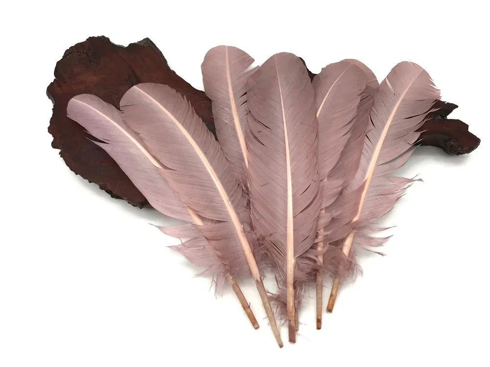 Soft dusty pink feathers for DIY crafts and fashion decor on a dark wood base.