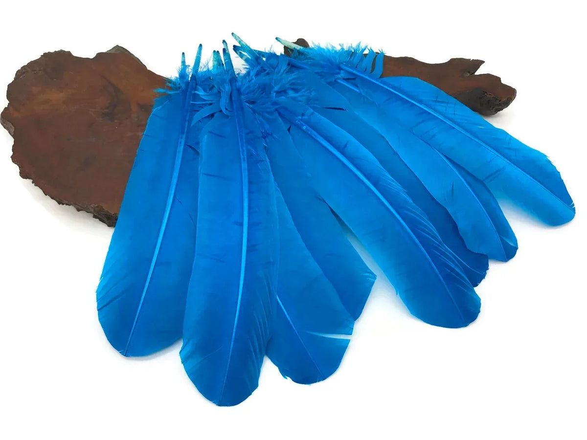 Vibrant blue craft feathers displayed on a rustic wooden base for DIY fashion and decor.
