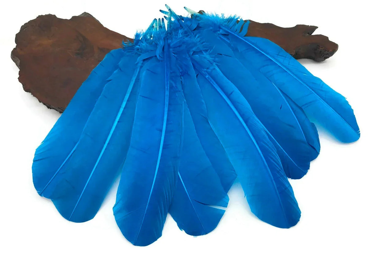 Vibrant blue craft feathers arranged on a dark wooden base for DIY fashion and décor.