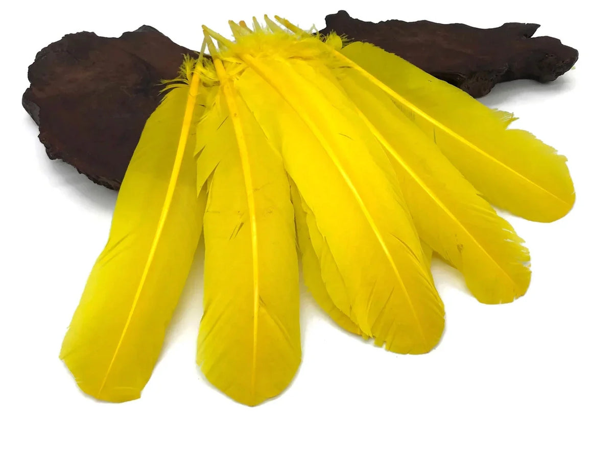 Vibrant yellow craft feathers arranged on a dark wood piece for DIY fashion and decor.